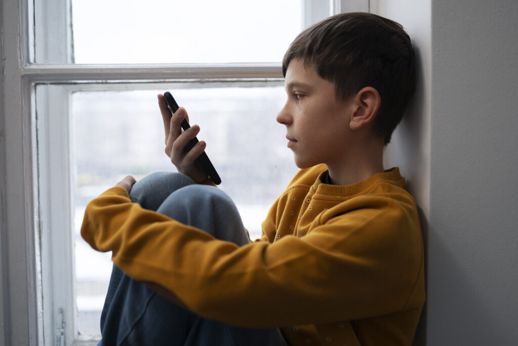 adolescent victime de cyberharcèlement en ligne et connecté sur son smartphone