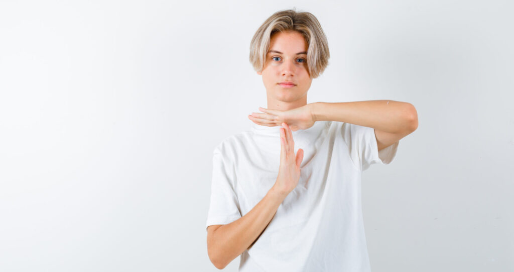 Adolescent faisant un geste de pause pour illustrer le débat sur l’interdiction des réseaux sociaux après la décision du Conseil constitutionnel.